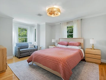 Bedroom with dusty-rose coverlet, blue loveseat, and Edgartown pillow