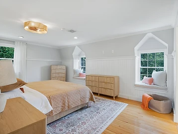 Bedroom with amber coverlet, two window-seat nooks, and orange throw