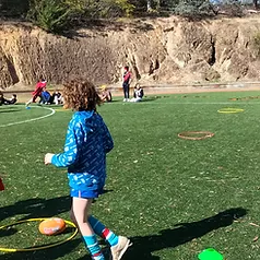 Students playing with hula hoops and footballs on the school turf during an outdoor activity