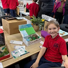 Student smiling at her science and geography project showcase