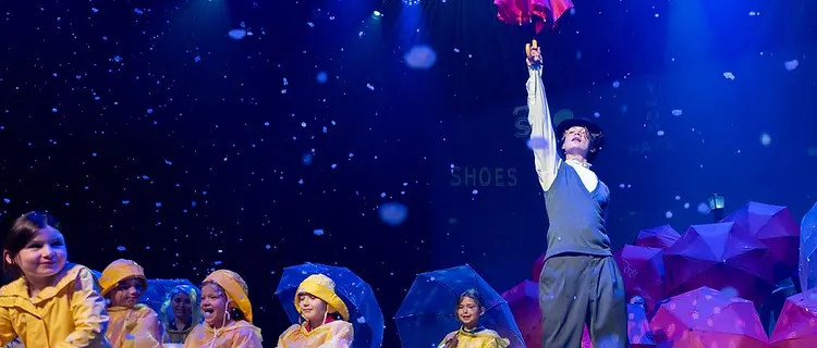 Rain scene with pink umbrellas and the ensemble in yellow slickers