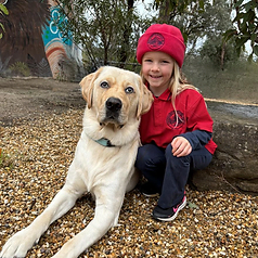 Student sitting with Winston the therapy dog on the rocks