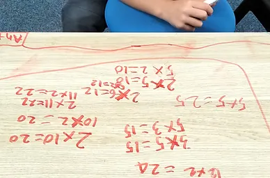 Student working through multiplication problems with red counters