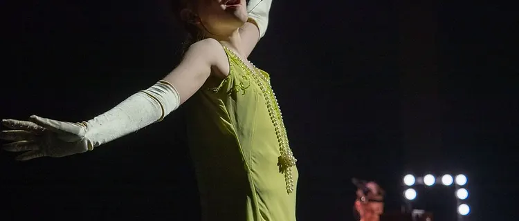 Soloist in a chartreuse beaded dress performing under the vanity lights