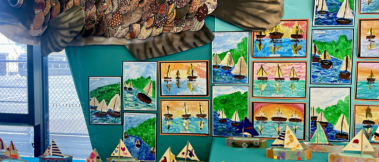 Student maritime art exhibition with sailboat paintings and fish sculpture
