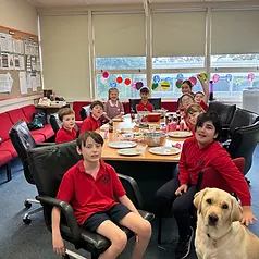 Students and Winston the therapy dog gathered around a classroom table
