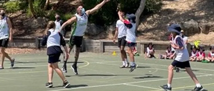 Students and coach contesting a shot during a basketball clinic