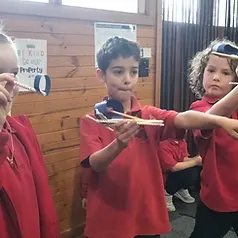 Students holding paper-and-straw airplanes during a classroom craft activity