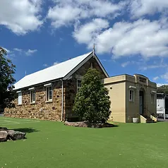 Historic sandstone school building with white roof and spire