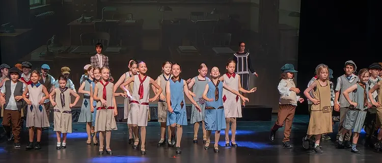 Full-stage ensemble of students in period costume during a school musical