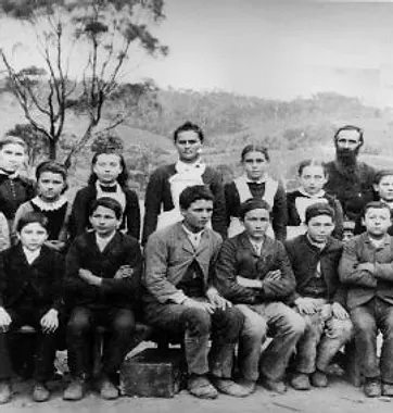 Historical group photograph of seated boys and standing girls with a teacher