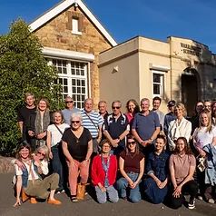Staff and community group photo in front of the historic school building
