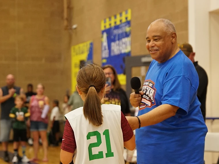 All-Star Experience community moment — a coach offers a young player the microphone