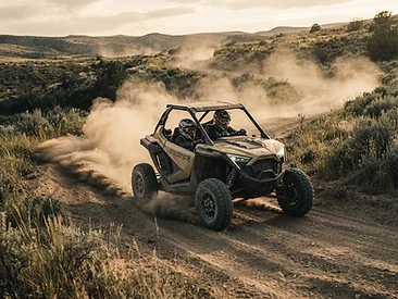 Side-by-side on a dirt trail kicking up dust