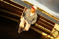 Max White on a seafront bench in golden light
