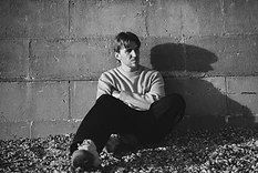 Max White seated against a wall in black and white