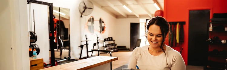 A Familia Fitness coach reviewing a client's progress at the studio reception desk