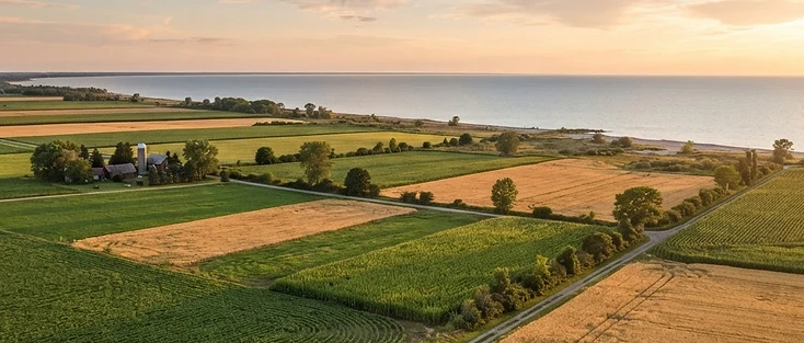A view of farmland meeting a calm Great Lake in the Southwestern Ontario region of Ontario, where Warwick is located.
