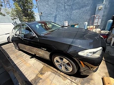 Front quarter view of a glossy black BMW 5-series after a full mobile detail
