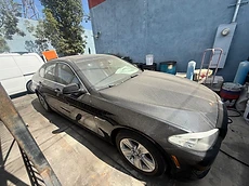 Black BMW sedan covered in dust before detailing by 213 Luis Mobile Detailing