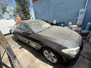 Black BMW sedan covered in dust before detailing by 213 Luis Mobile Detailing