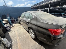 Rear view of a dusty black BMW sedan before a mobile detailing service