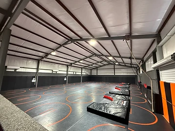 Wide view of the Dead Shot training facility with climbing rope and padded walls