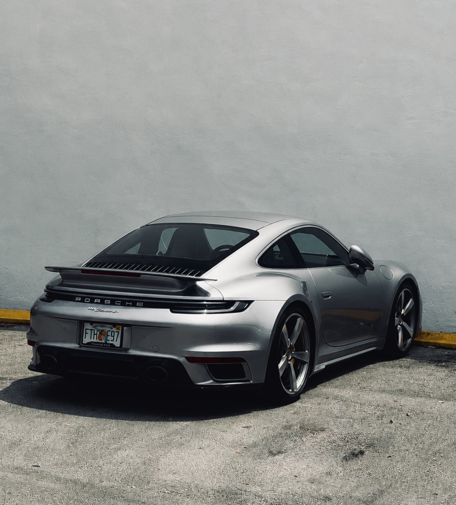 Silver Porsche 911 parked against a concrete wall