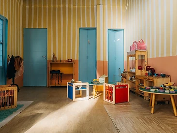 Sala de brincar com paredes listradas, portas azuis e cozinha de madeira