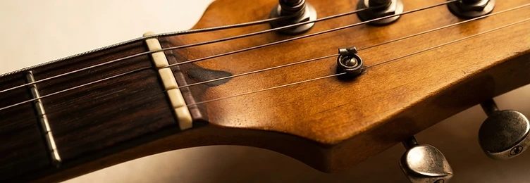 Macro close-up of a vintage Gibson-style guitar headstock with tuning pegs and warm studio lighting