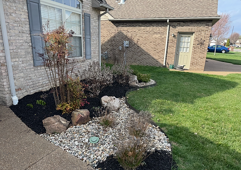 Landscaped garden bed with black mulch, boulders and rock drainage installed by Get It Done Services