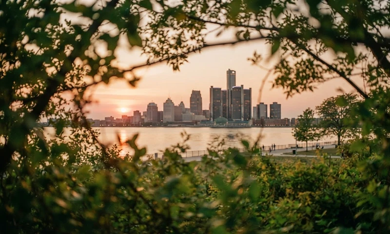 Detroit Riverwalk at golden hour filtered through green foliage