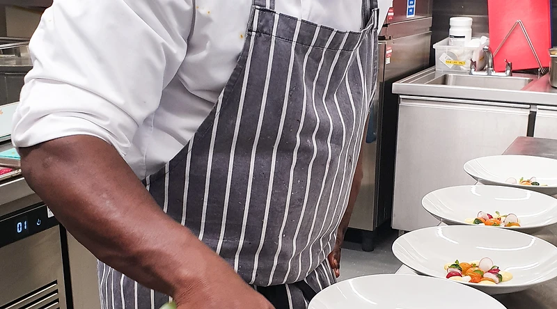 Chef Tunde plating a dish in a professional kitchen