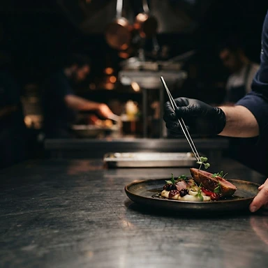 Chef precisely plating a dish in a warm, quiet kitchen