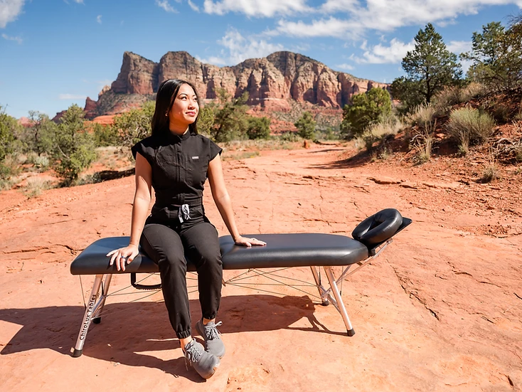 Dr. Paula Hale seated on her portable chiropractic table outdoors in the Arizona landscape