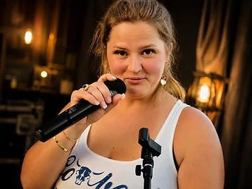 Faye close-up with microphone under warm stage light