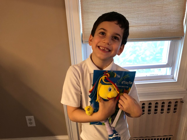 A young reader holding “The Psst-psst... of Toley Ranz: Stops Bullying.”