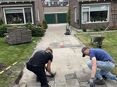 Bestraten van een oprit tussen woningen met tegels en een trilplaat