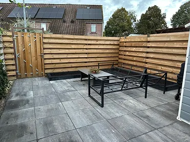 Afgewerkte tuin met nieuwe schuttingen, bestrating en terrasmeubilair