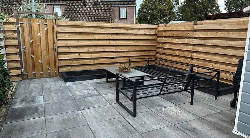 Afgewerkte tuin met nieuwe schuttingen, bestrating en terrasmeubilair