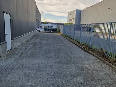Verhard pad tussen bedrijfsgebouwen op een bedrijventerrein met hekwerk