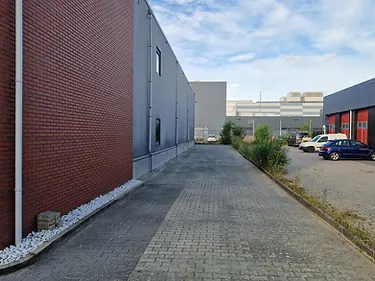 Bestraat bedrijventerrein met klinkers bij een bedrijfspand met rode muur