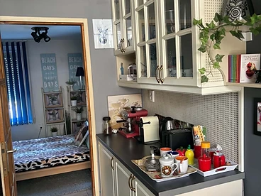 Konyhapult konyhai gépekkel, nyitott ajtó a hálószoba felé