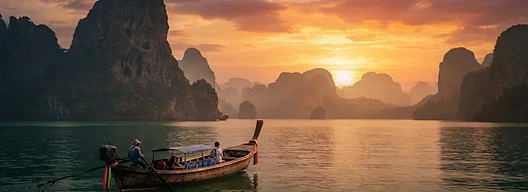 Thai longtail boat on emerald water beneath limestone karsts at sunset