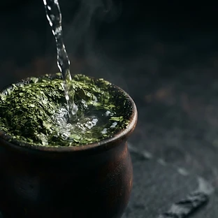 Agua rompiendo la superficie de la yerba mate en un mate oscuro