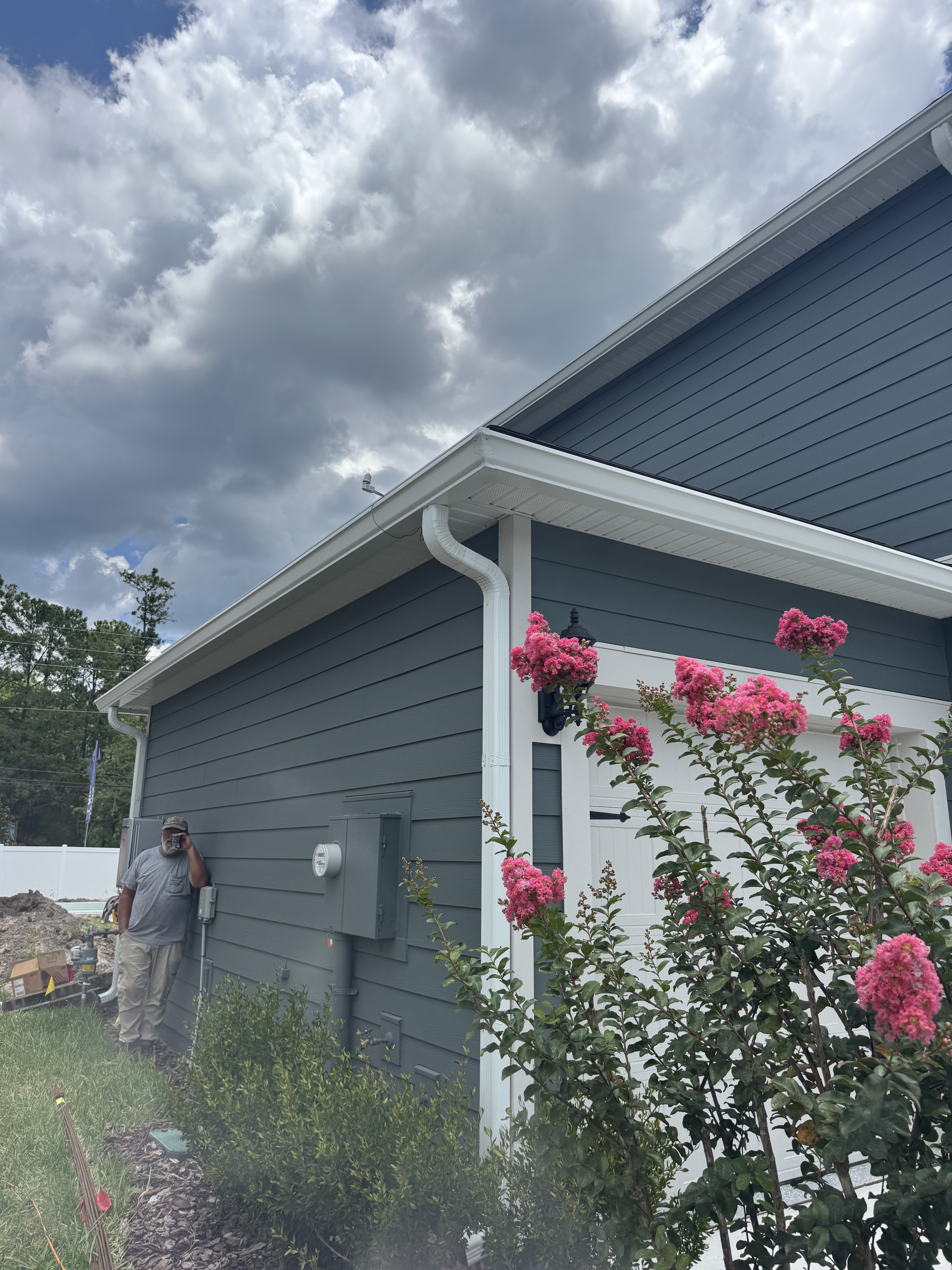 New white seamless gutter and downspout on a gray-sided Jacksonville home