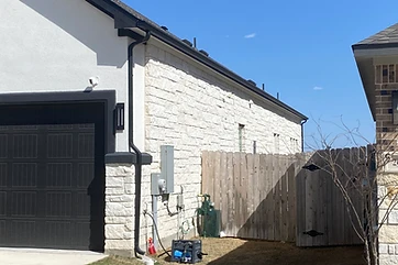 Black seamless gutters on a white stucco and stone home with a black garage door