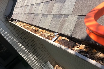 Gutter packed with leaves and debris before cleaning on an Austin-area home