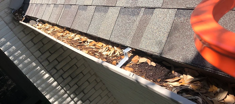Gutter packed with leaves and debris before cleaning on an Austin-area home
