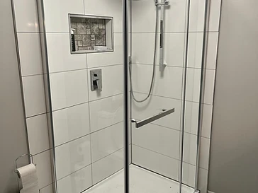 Rénovation de douche en coin avec céramique blanche réalisée par Exceco Construction